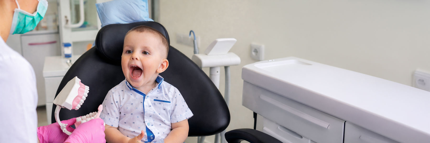 Baby sitting in a dentist chair with his mouth open