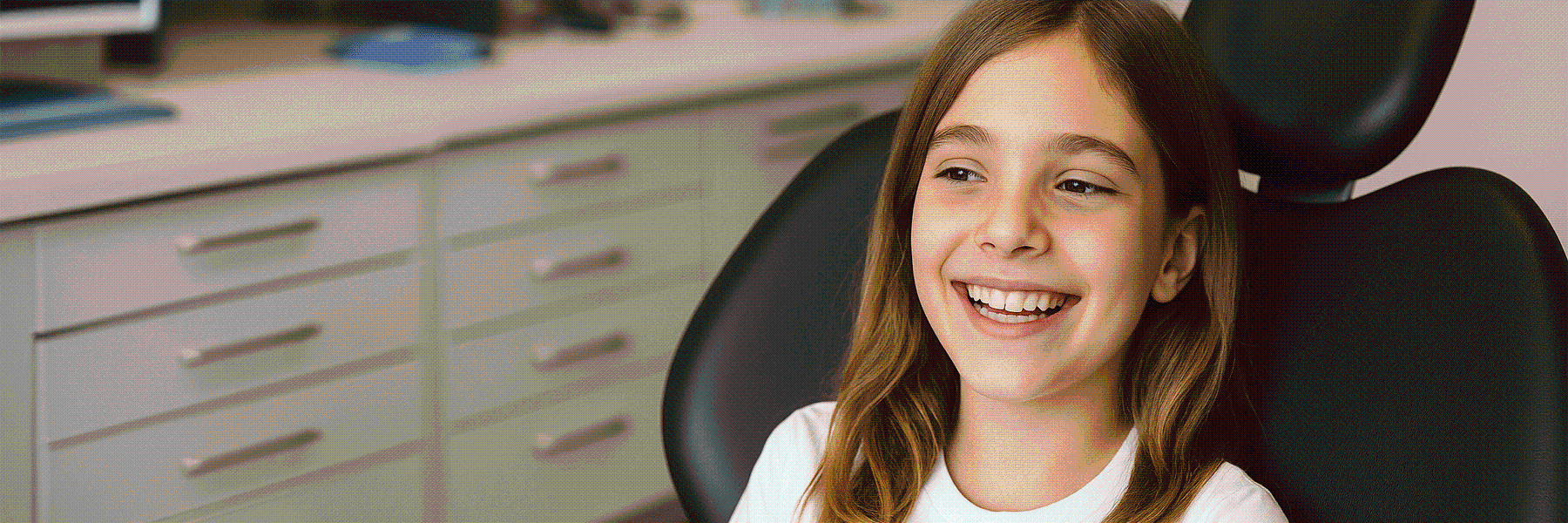 Girl smiling in a dental chair in an exam room